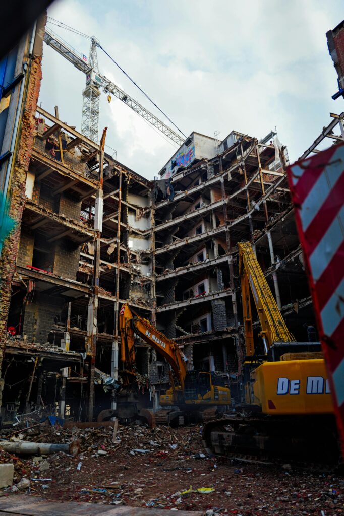 Destruction scene with construction cranes and excavators at a building site.