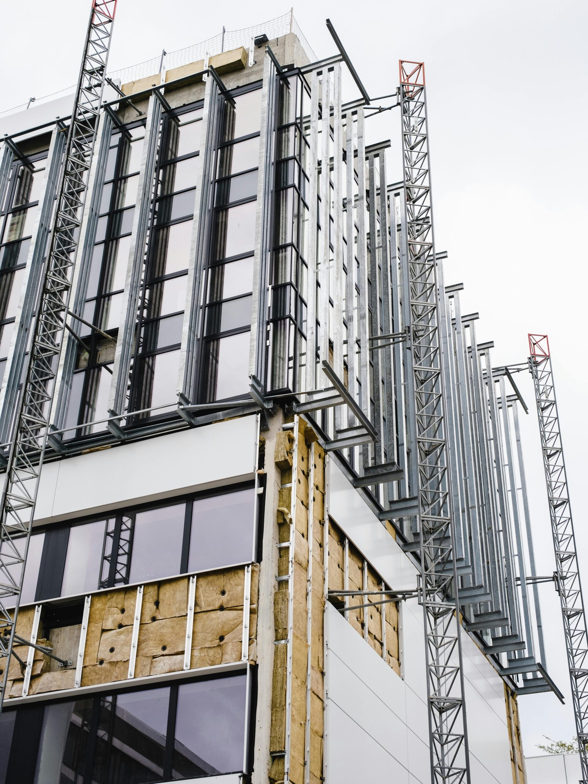 Low angle shot of a modern building under construction with glass windows and steel frames.